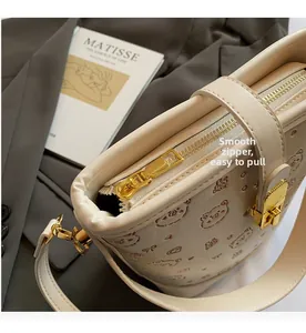 Detail of smooth golden zipper and textured embossed leather on stylish cream bucket bag