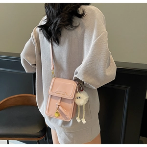Pink glossy leather crossbody bag with FASHION & BAGS logo and cute plush monster charm
