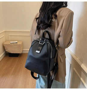 Modern black backpack with pebble grain texture shown on model in a minimalist setting