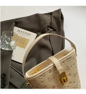 Detail of cream bucket bag showing bear embossed texture and golden metal lock