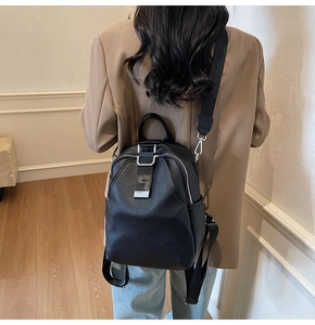 Detail of black pebbled leather backpack with silver zippers and stylish metal buckle