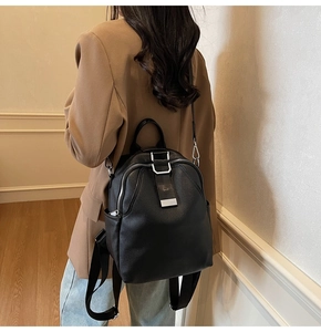 Detail of black pebbled leather backpack featuring silver metal buckle and adjustable straps