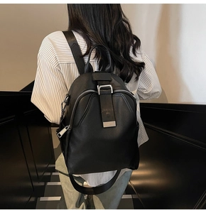 Side view of woman wearing a black lychee leather backpack with metal buckles