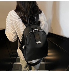 Detail of black pebbled leather backpack with silver zippers and side pocket on model