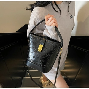 Detail of black glossy leather bucket bag featuring a 3D embossed bear and gold hardware