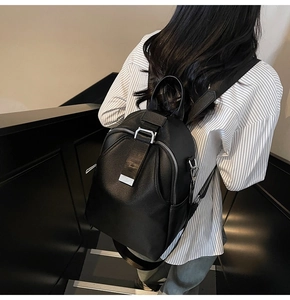 Detail of a textured black PU leather backpack with silver hardware on a female model