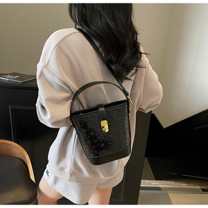 Detail of black bucket bag with embossed bear patterns and golden metal turn-lock