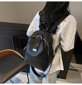 Close-up of a black leather backpack with lychee texture and metallic clasp detail