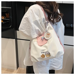 Détail du sac fourre-tout blanc avec bretelles roses et motifs brodés de capybara