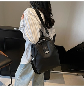 Detail of black textured backpack featuring a silver metal buckle and side zip pocket