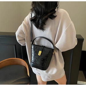 Detail of black embossed bucket bag featuring bear patterns and golden twist lock clasp