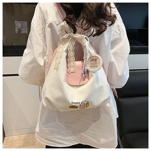 Détail de l'arrière du sac bandoulière blanc et rose avec nœud en dentelle et pendentif