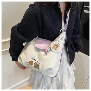 Détail du sac bandoulière blanc et violet avec broderie cartoon et charme capybara
