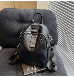 Detail of black pebbled leather backpack with silver zippers and side pocket on a chair