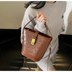 Detailed view of brown bucket bag featuring 3D embossed bear patterns and metal twist lock