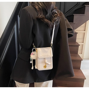 Chic cream vertical mini square phone bag with plush charm and stylish gold pendant detail