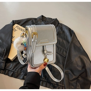 Close-up of silver crackle leather mini square bag with plush charm on leather jacket