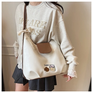 Détail du sac fourre-tout en PU crème avec broderie chat et nœud en dentelle brune