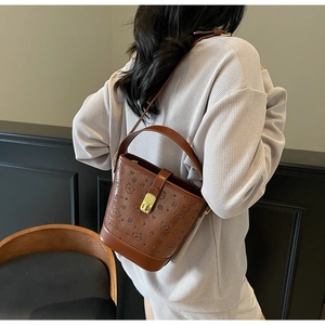 Detailed view of brown leather bucket bag with embossed bear pattern and gold metal lock