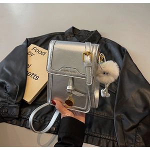 Silver mini crossbody bag with gold buckle, plush charm, and metallic texture detail