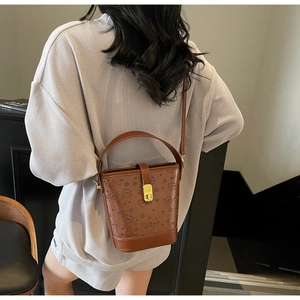 Detail view of brown bucket bag featuring embossed bear patterns and gold metal clasp