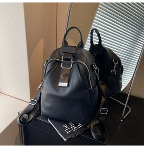 Close-up of black litchi grain leather backpack with silver metal buckle and side pocket