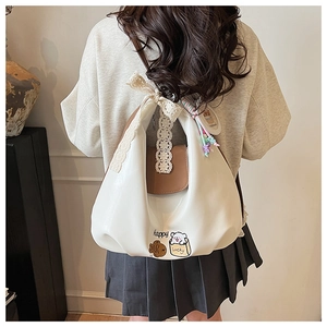Détail du sac en cuir PU crème avec imprimé ours, nœud en dentelle et breloque colorée