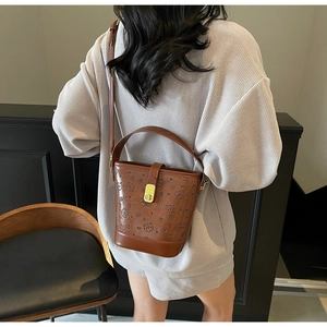 Detail of dark brown bucket bag with embossed bears and gold buckle on a model