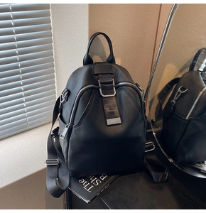 Close-up of black pebble leather backpack featuring silver zippers and side pocket detail