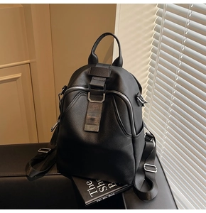 Detail of black pebbled leather backpack featuring silver zippers and adjustable straps