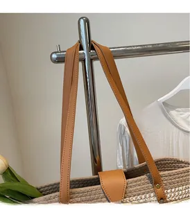 Close-up of woven tote bag featuring brown leather handles and sturdy metal rivets