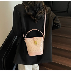 Close-up of pink bucket bag with embossed bear patterns and golden metal hardware