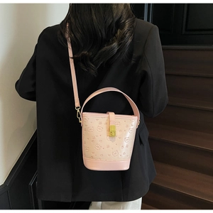 Detail of pink leather bucket bag featuring embossed bear patterns and gold twist lock