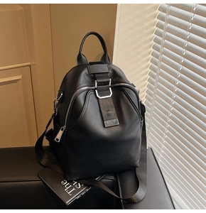 Detail of black pebbled leather backpack with silver hardware and vertical web straps