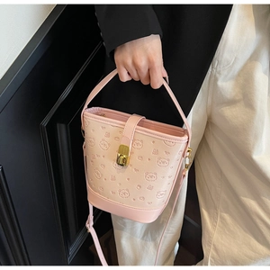 Detail of pink embossed PU leather bucket bag with bear patterns and gold buckle