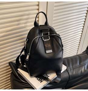 Detail of black pebbled leather backpack with silver buckle in a modern urban setting