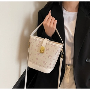 Detail of a beige bucket bag with pink bear prints and a gold twist-lock closure