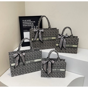 Detail view of four-piece black and white canvas tote set with chic ribbon decorations