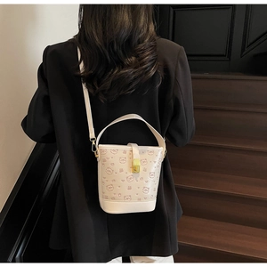Detail view of white bucket bag with pink bear prints and golden metal clasp