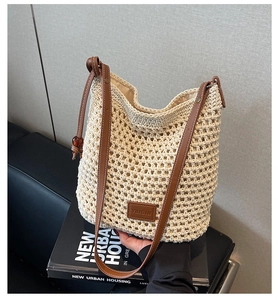 Détail du sac seau en tricot ajouré avec bandoulière en cuir brun et logo