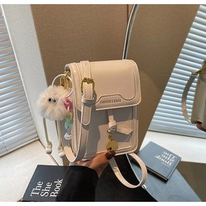 Detail of cream PU leather phone bag with metal buckle and plush doll accessory