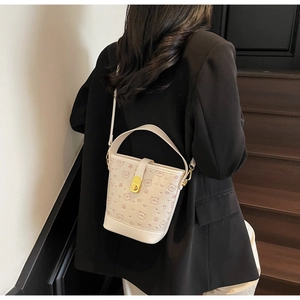 Detail of cream bucket bag featuring embossed cartoon bears and gold twist lock closure