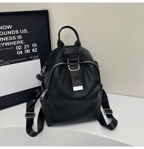 Close-up of black leather backpack detailing silver buckles and nylon straps