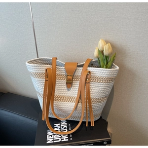 Detail of hand-woven straw tote bag with leather straps and decorative floral elements