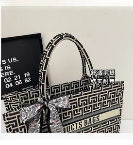 Detail of canvas tote bag featuring geometric maze patterns and decorative silk scarf wrap