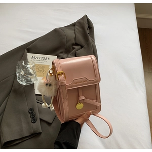 Pink mini square bag featuring adjustable strap and plush pendant in stylish scenario