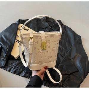 Detail of white bucket bag featuring embossed pink bears and gold metal twist lock