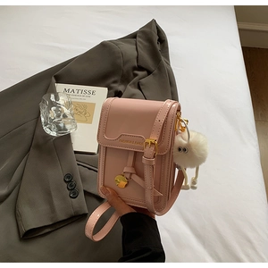 Detailed view of pink leather phone bag with gold clasp and white fluffy charm pendant