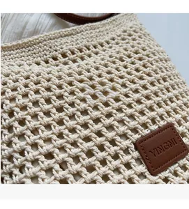 Détail du sac seau en maille beige ajourée avec un écusson logo en cuir marron chic