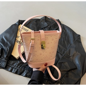 Detail of pink bucket bag featuring teddy bear embossing and gold twist lock closure